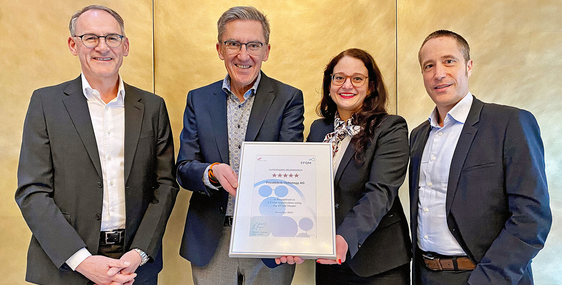 Vier Personen stehen vor einer goldenen Wand