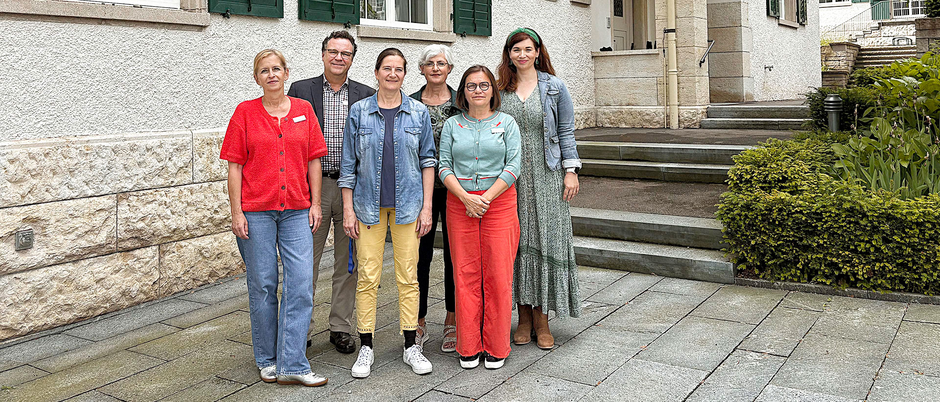 Eine Gruppe von Menschen stehen vor einem Gebäude.