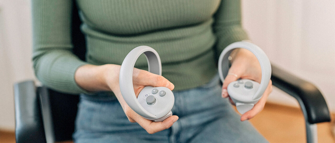 Eine Person hat Controller für eine VR-Brille in der Hand.