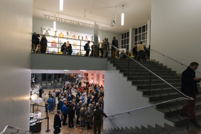 Menschen in einem Museum auf zwei Etagen, verbunden mit einer Treppe.